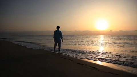 Wide view of a person walking along a coastal path at sunrise